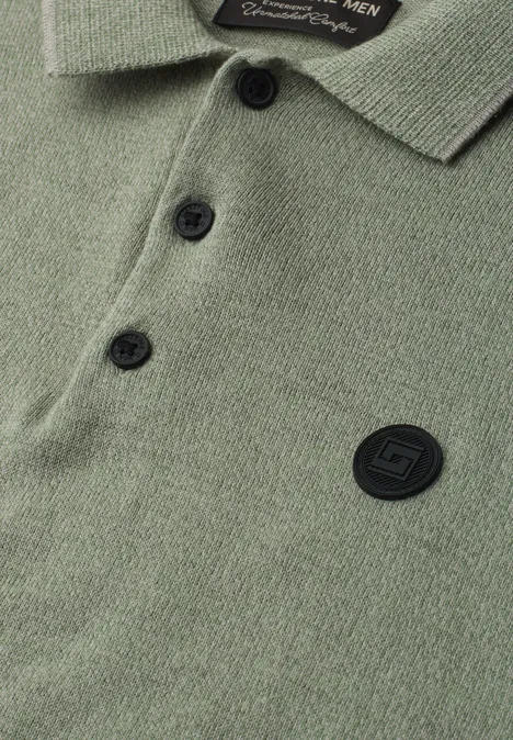 Gebreid poloshirt in mouliné-look willow green Close-up van een olijfgroen poloshirt met knopenlijst, kraag en ronde, zwarte logopatch.