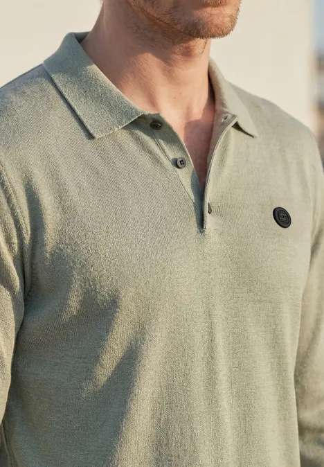 Gebreid poloshirt in mouliné-look willow green Een man draagt een lichtgroene, gestructureerde polo met open kraag en een klein rond zwart logo op de borst.