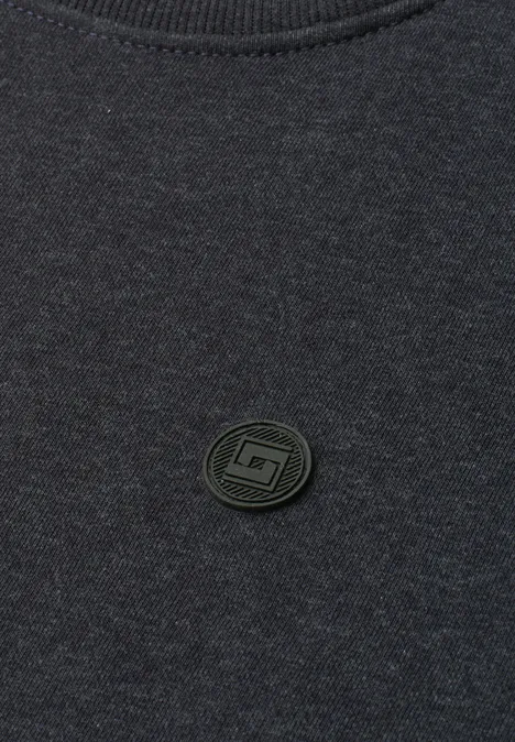 T-shirt gris foncé avec petit écusson rond noir à logo au centre.