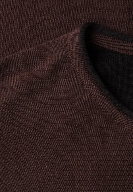 Nahaufnahme eines dunkelbraunen, fein gestrickten Sweaters mit Rundhalsausschnitt.