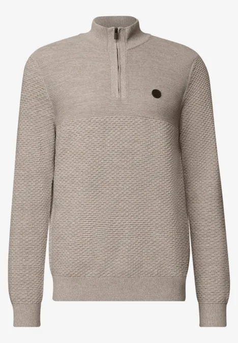 Beiger Strickpullover mit halbem Reißverschluss, feinem Strukturmuster und kleinem runden Logo-Patch.