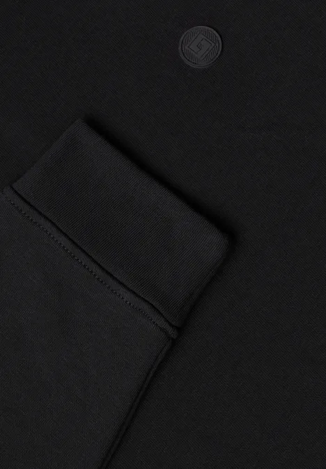 Nahaufnahme eines schwarzen Kleidungsstücks mit eingenähter Tasche und dezenter Logoprägung