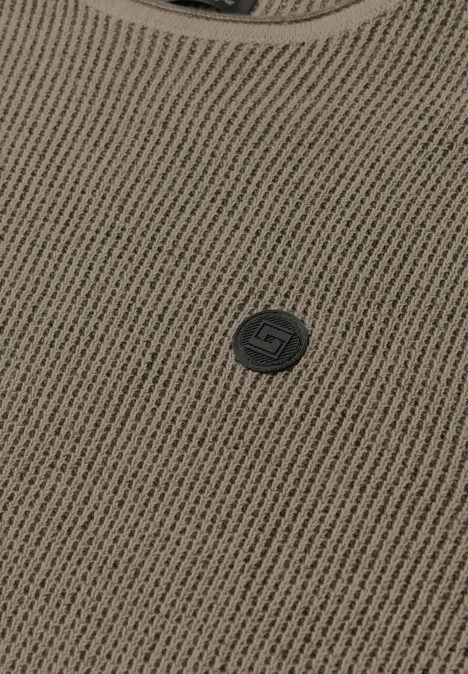 Nahaufnahme eines braunen Strickoberteils mit Rundhalsausschnitt und kleinem, dunkelgrauem Logo-Button.
