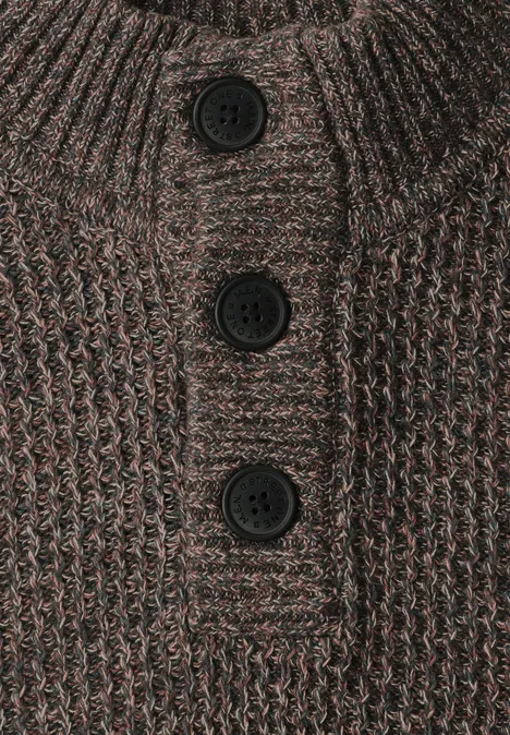 Pull à col roulé et texturé shadow brown Nahaufnahme eines braunen, grob gestrickten Pullovers mit Stehkragen und drei schwarzen Knöpfen.