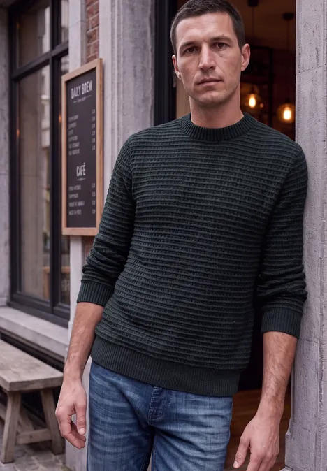 Chenille-trui met wafelstructuur dark ink blue Ein Mann in grünem Pullover lehnt lässig an einer Hauswand vor einem Cafe