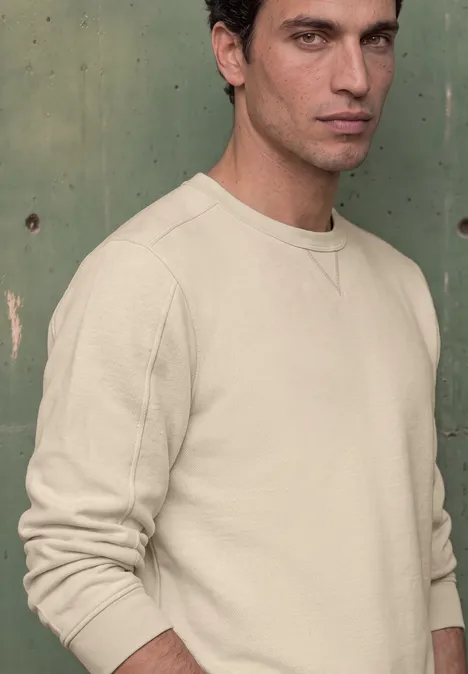 Sweat-shirt en tissu éponge avec détails en tricot côtelé canvas beige Jeune homme aux cheveux noirs portant un sweat-shirt beige devant un mur vert.