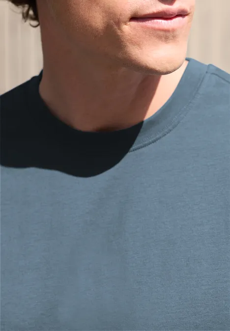 Gedeeltelijke weergave van een man in een blauw T-shirt, nek en onderkant van het gezicht voor een lichte achtergrond