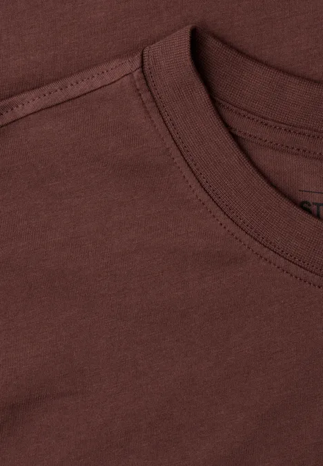 Close-up van een bruin T-shirt met ronde hals en zichtbare stiksels.