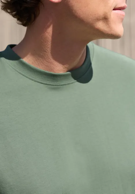 Zijaanzicht van een persoon in een groen T-shirt, zicht op bovenlichaam en kin.