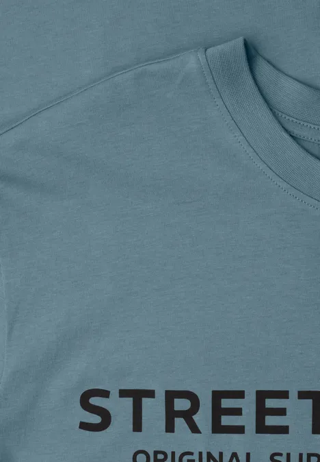 Hellblaues T-Shirt mit schwarzem Schriftzug 'STREET', Detailaufnahme von Kragen und Schulter.