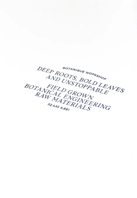 Wit T-shirt met blauwe tekst 'BOTANICAL WOW' en Engelse slogan over wortels, bladeren en grondstoffen.