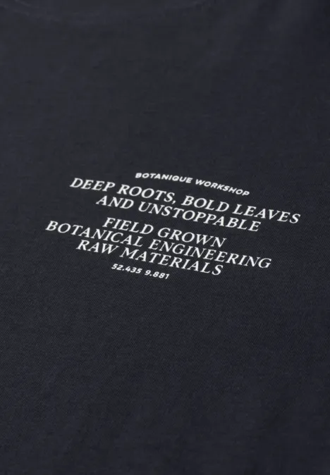 Zwart T-shirt met witte tekst over botanische groei: diepe wortels en stevige bladeren.