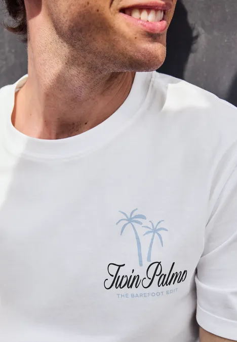Mann im weißen T-Shirt mit Logo 'Twin Palms' und zwei Palmen als Grafik auf der Brust.