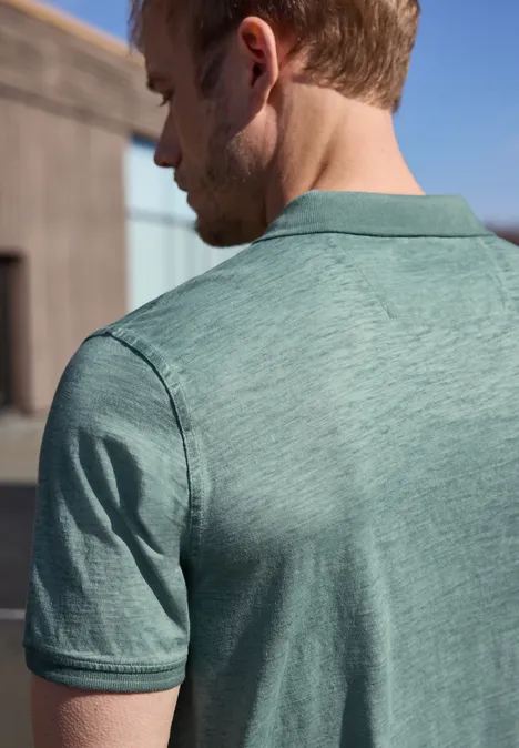 Een man is van achteren te zien, hij draagt een lichtgroen poloshirt voor een zonnige buitenomgeving.