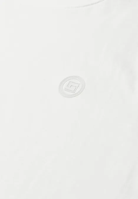 Een eenvoudig wit T-shirt met een klein rond logo op de borst.