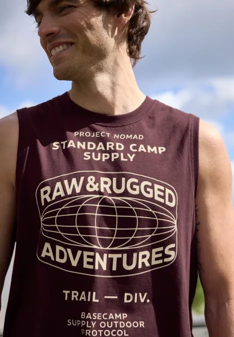 Bovenlichaam in bordeaux mouwloos shirt met opschrift "RAW & RUGGED ADVENTURES" en gestileerde wereldbol.