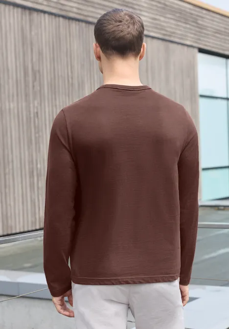 Effen shirt met lange mouwen en ronde hals maroon brown Een man in een bruine trui van achteren bij een muur.