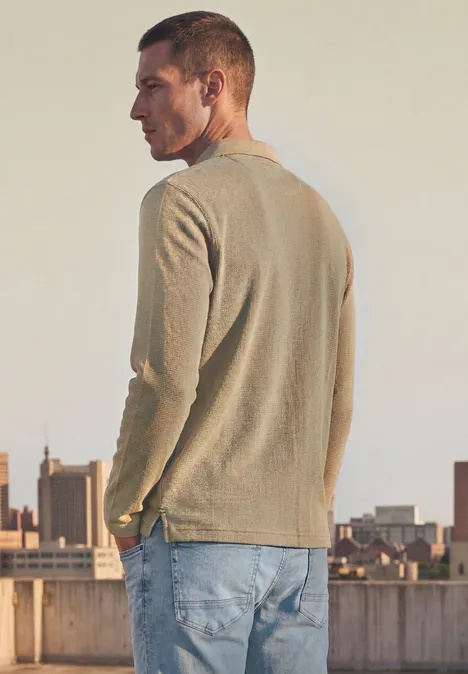 Poloshirt met lange mouwen en ritsdetail antique beige Man in beige trui en spijkerbroek op een dak met uitzicht op de stad.