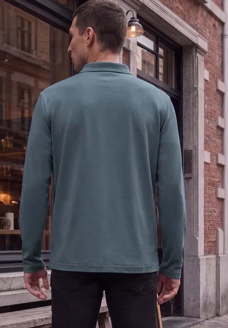Ein Mann steht in einem grünen Langarm-Poloshirt vor der Schaufensterfront eines Cafés aus rotem Backstein.