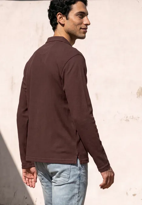 Langarm Poloshirt in Unifarbe maroon brown Ein Mann im Profil trägt braunes Hemd und Jeans vor einer hellen Wand.