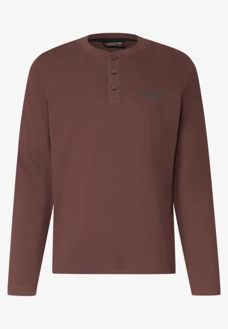 Een kastanjebruine Henley longsleeve met ronde hals en knoopsluiting.