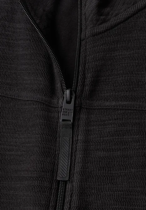 Langarm Jacke mit Stehkragen basic black Nahaufnahme eines schwarzen Reißverschlusses auf strukturiertem Stoff.