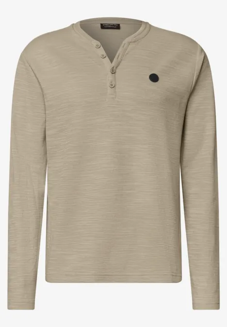 Beiges langärmliges Henley-Shirt mit Knopfleiste am Kragen und kleinem Logo-Patch auf der Brust.