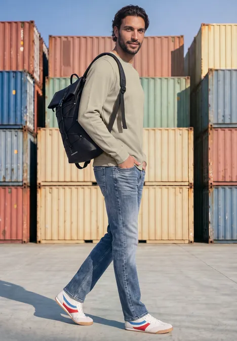 Langarm Shirt mit Popcorn-Struktur classic beige Ein Mann mit Rucksack, Jeans und Sneakern steht seitlich vor bunten Frachtcontainern.