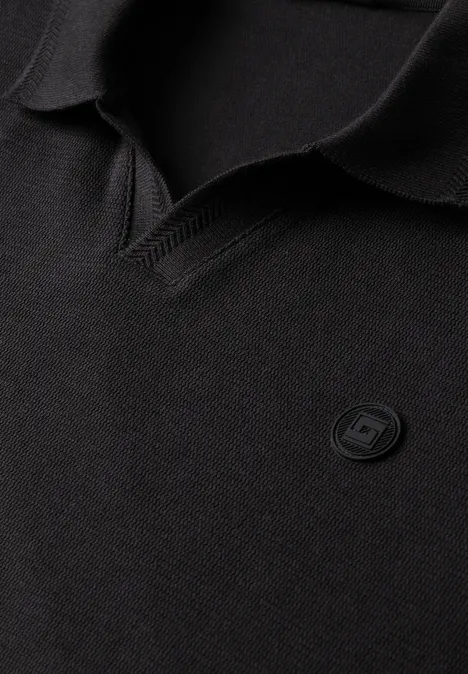 Schwarzes Polohemd mit V-Ausschnitt-Kragen und dezentem, rundem Logo-Badge auf der Brust.