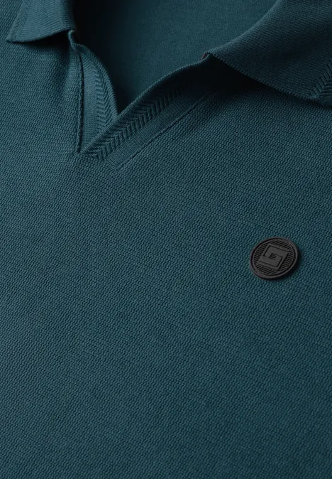 Grünes Poloshirt mit klassischem Kragen, V-Ausschnitt-Struktur und kleinem, schwarzem Logo-Button.