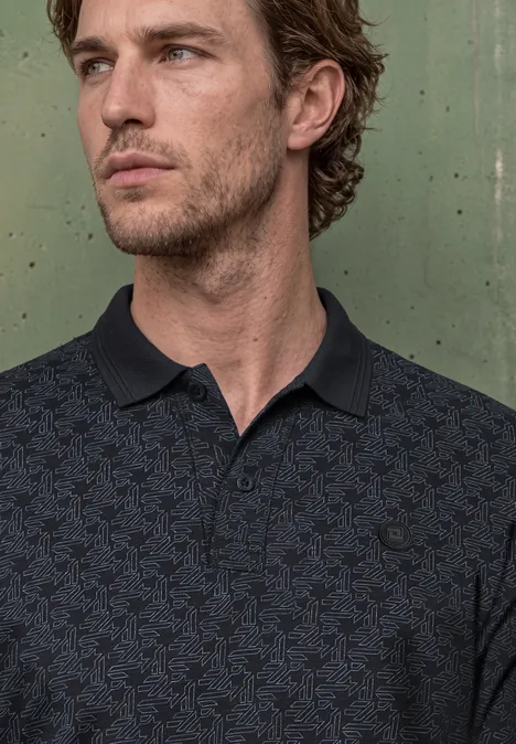 Een bedachtzame man met kort bruin haar draagt een donker poloshirt en kijkt zijwaarts.