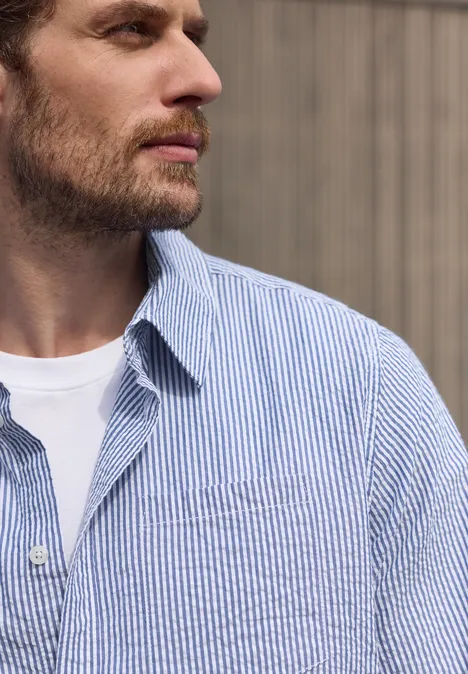 Langarm Hemd in Seersucker-Qualität bright white Profilaufnahme eines bärtigen Mannes mit weißem T-Shirt und blau-weiß gestreiftem Hemd vor hellem Hintergrund