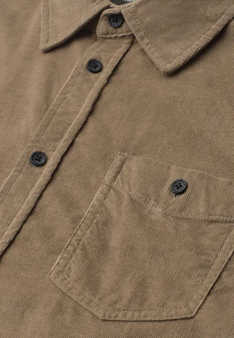 Effen corduroy overhemd met lange mouwen brass brown Close-up van een bruin ribfluwelen overhemd met kraag, knopenrij en borstzak.