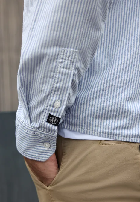 Overhemd met lange mouwen en streepjespatroon bright white Een man draagt een lichtblauw-wit gestreept overhemd met beige broek, hand in de zak