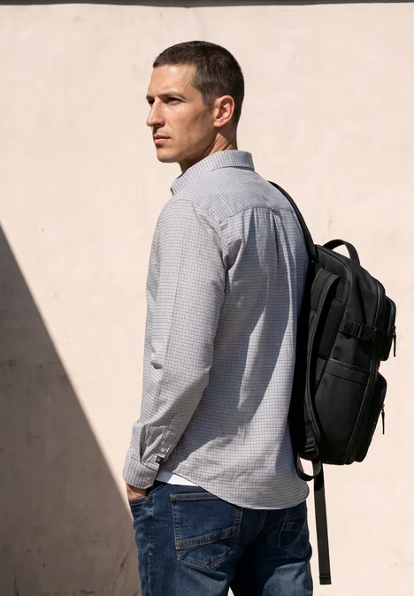 Langarm Popeline Hemd mit Print bright white Junger Mann in grauem Hemd mit schwarzem Rucksack steht vor heller Wand und blickt über die Schulter.