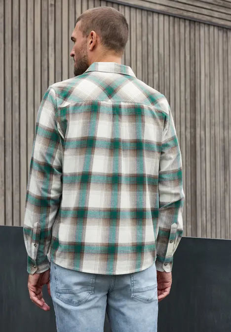 Overhemd met lange mouwen, borstzakken en ruitjespatroon bright white Een man met de rug naar de camera draagt een geruit overhemd en jeans voor een houten gevel.