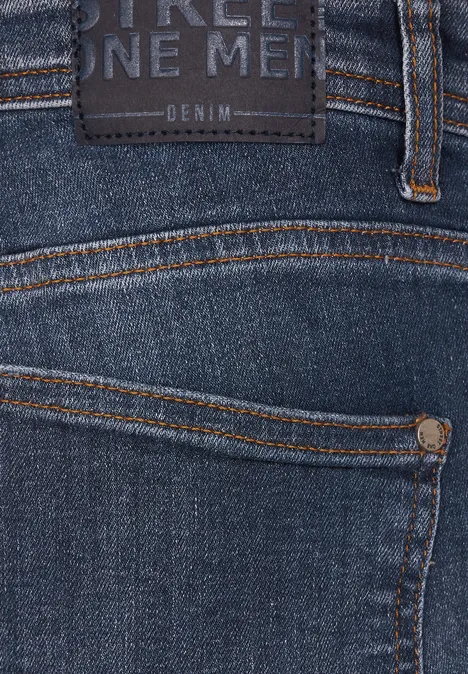 Gros plan sur un jean bleu avec une étiquette et des coutures orange.