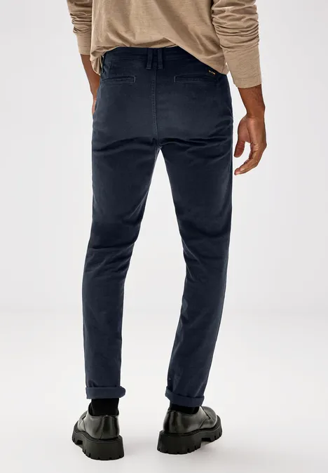 Homme en pantalon bleu foncé et pull beige vu de dos.