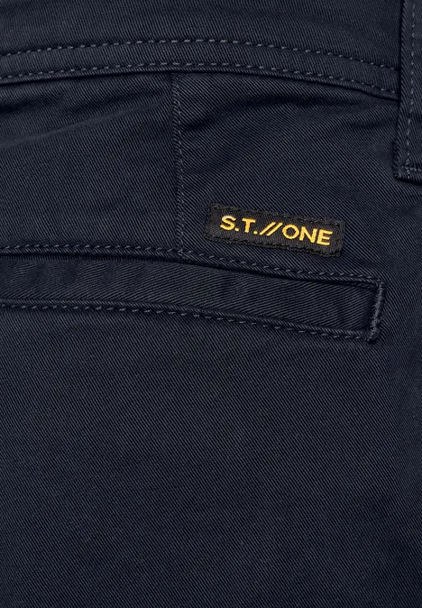 Gros plan sur une poche de pantalon foncé avec étiquette S.T.ONE jaune.