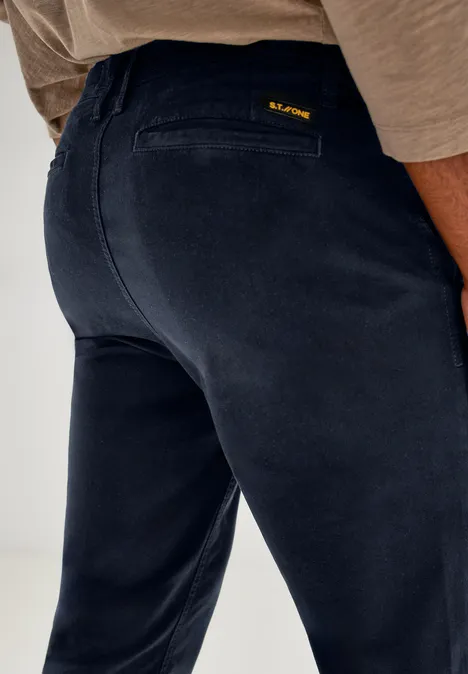 Gros plan sur un pantalon bleu foncé vu de dos, avec un haut beige.