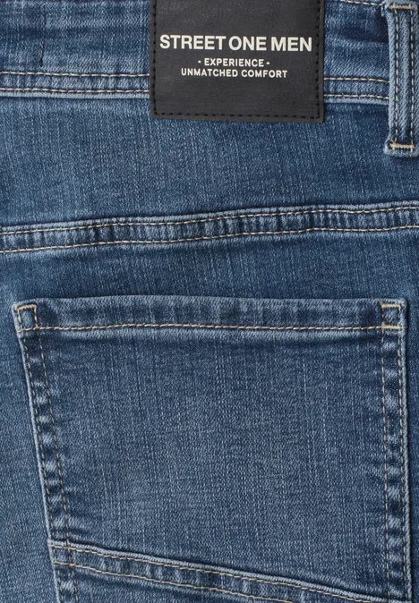 Gros plan d'un jean bleu avec une étiquette 'STREET ONE MEN' au-dessus de la poche arrière.