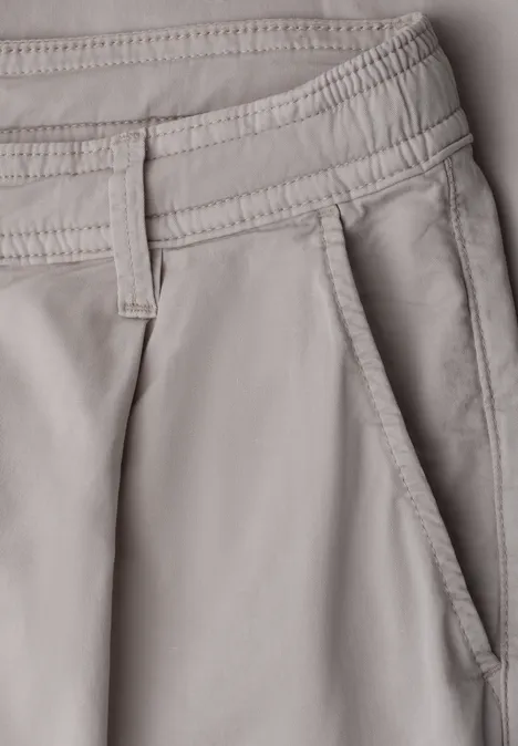 Pantalon beige avec poche latérale et passants de ceinture, coutures discrètes.