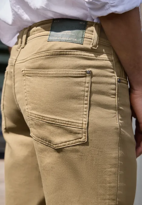 Close-up van een beige broek met zichtbare achterzak, rugaanzicht