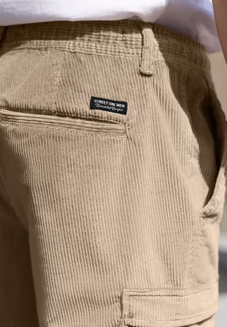 Gros plan d'un pantalon en velours beige clair avec poche arrière et petite étiquette noire.