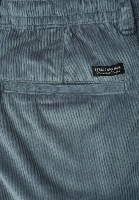 Gros plan d’un pantalon en velours côtelé gris-bleu avec poche arrière et étiquette de marque noire