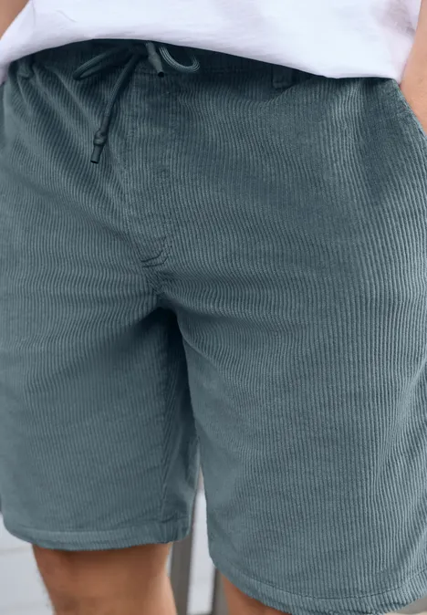 Short en velours côtelé vert avec cordon et poches, porté avec un haut blanc