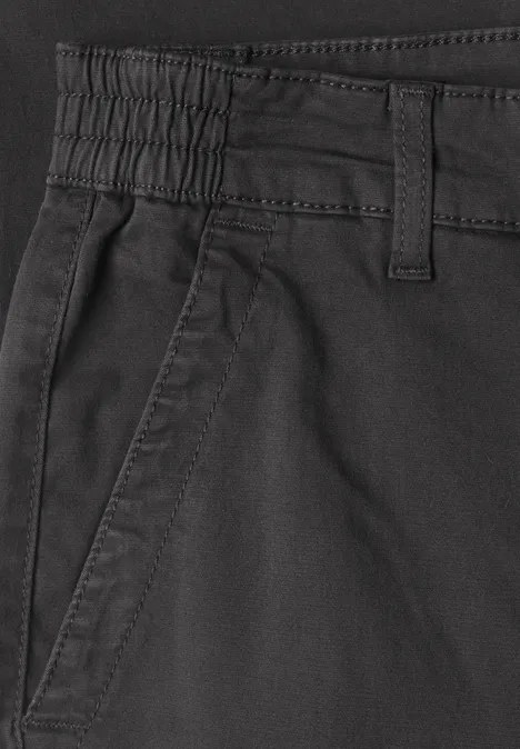Close-up van een zwarte broek met elastische taille, riemlussen en zijzak.