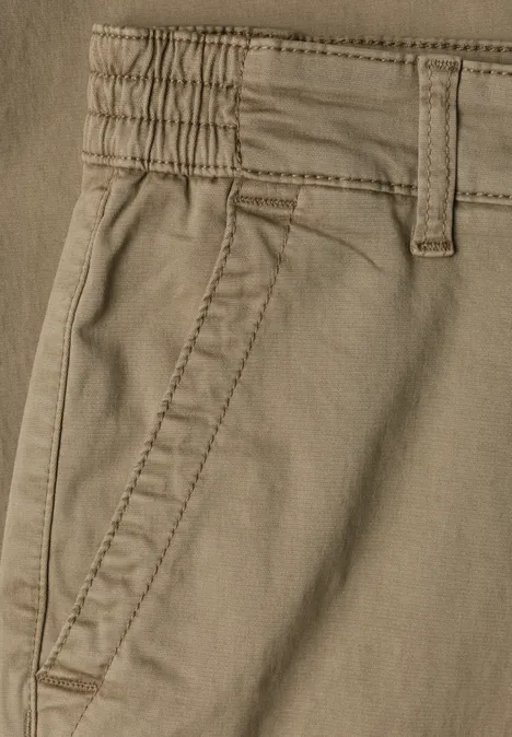 Close-up van een lichtbruine broek met zijzak en ceintuurlussen.