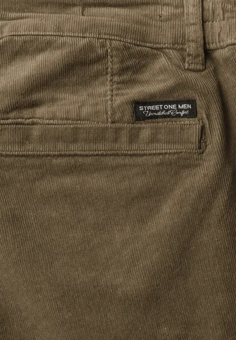 Pantalon chino en velours côtelé avec plis marqués au fer brass brown Gros plan sur un pantalon en velours côtelé vert olive, poche arrière et étiquette de marque.