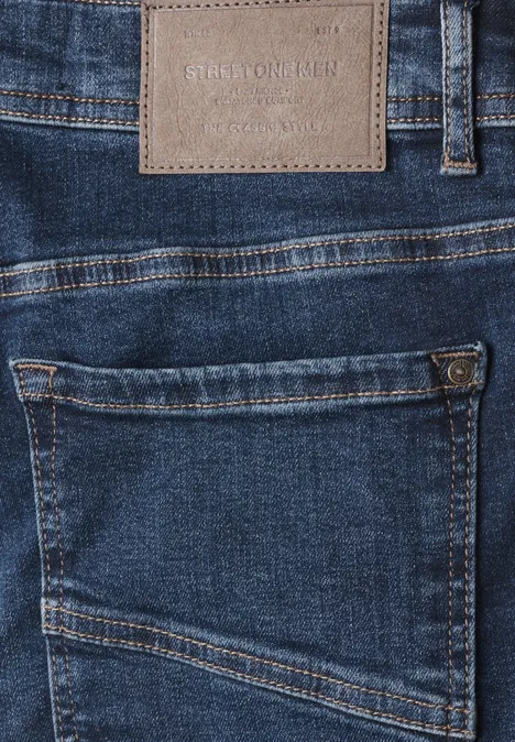 Jean Slim Leg à coupe ajustée indigo blue wash Gros plan sur un jean bleu avec poche arrière appliquée et étiquette en cuir.